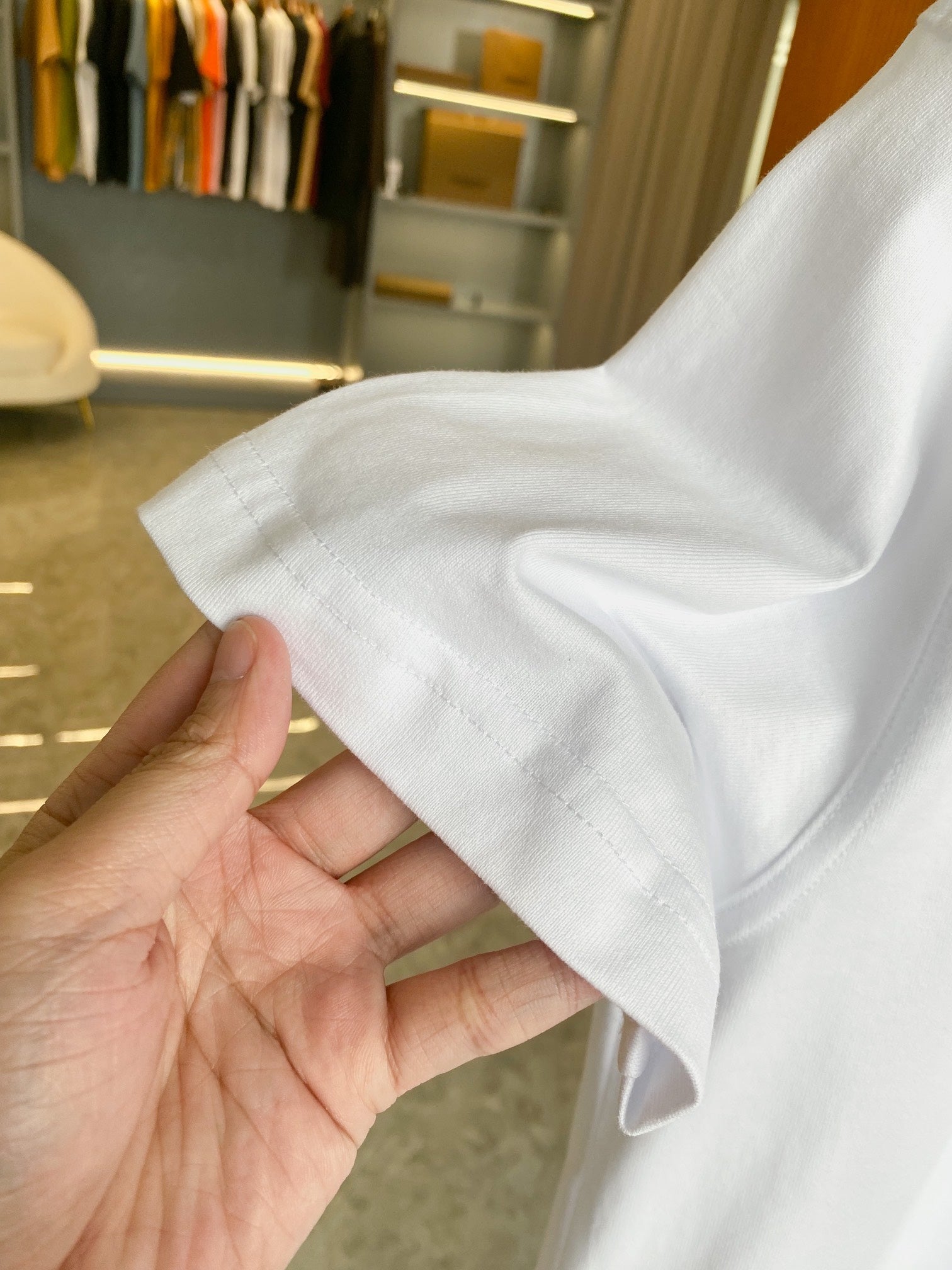 White short-sleeve T-shirt held by hand, showing soft fabric and sleeve hem.
