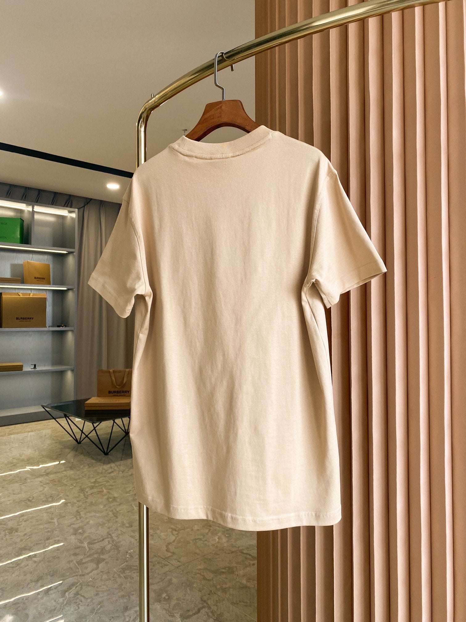 Light beige short-sleeve crewneck T-shirt front view on hanger with small chest logo
