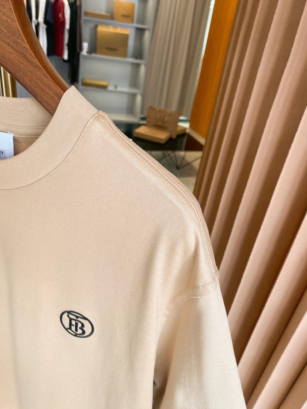 Light beige short-sleeve T-shirt with chest logo on sleeve seam, close-up