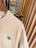 Light beige short-sleeve T-shirt with chest logo on sleeve seam, close-up