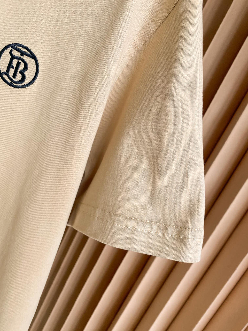 Light beige T-shirt sleeve with small chest logo and stitched hem detail