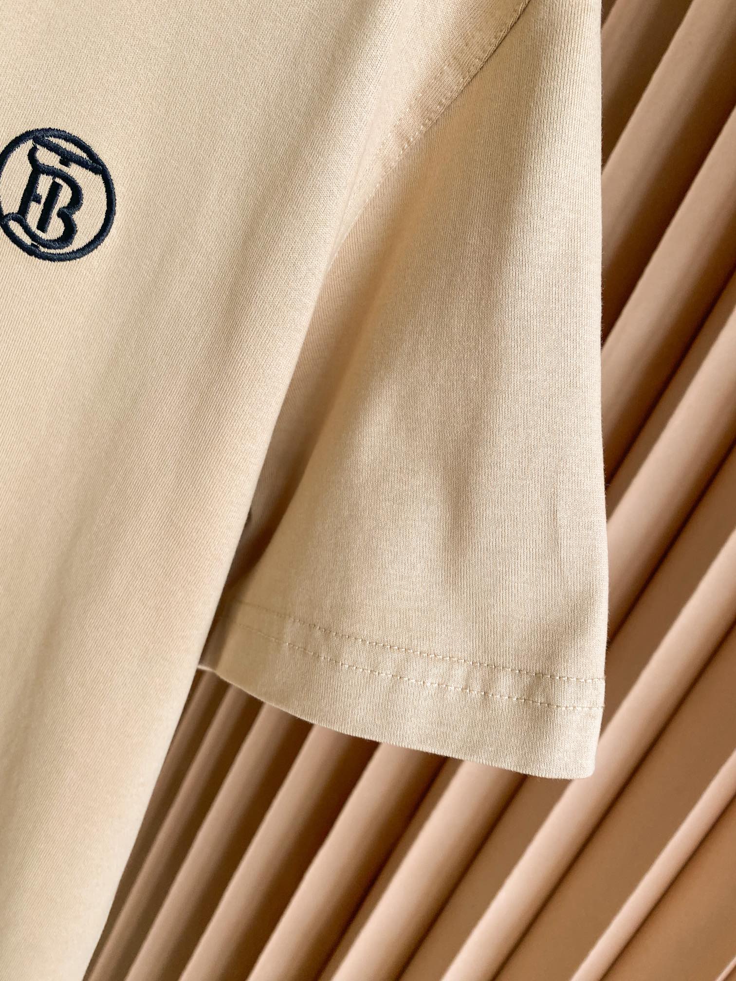 Light beige T-shirt sleeve with small chest logo and stitched hem detail