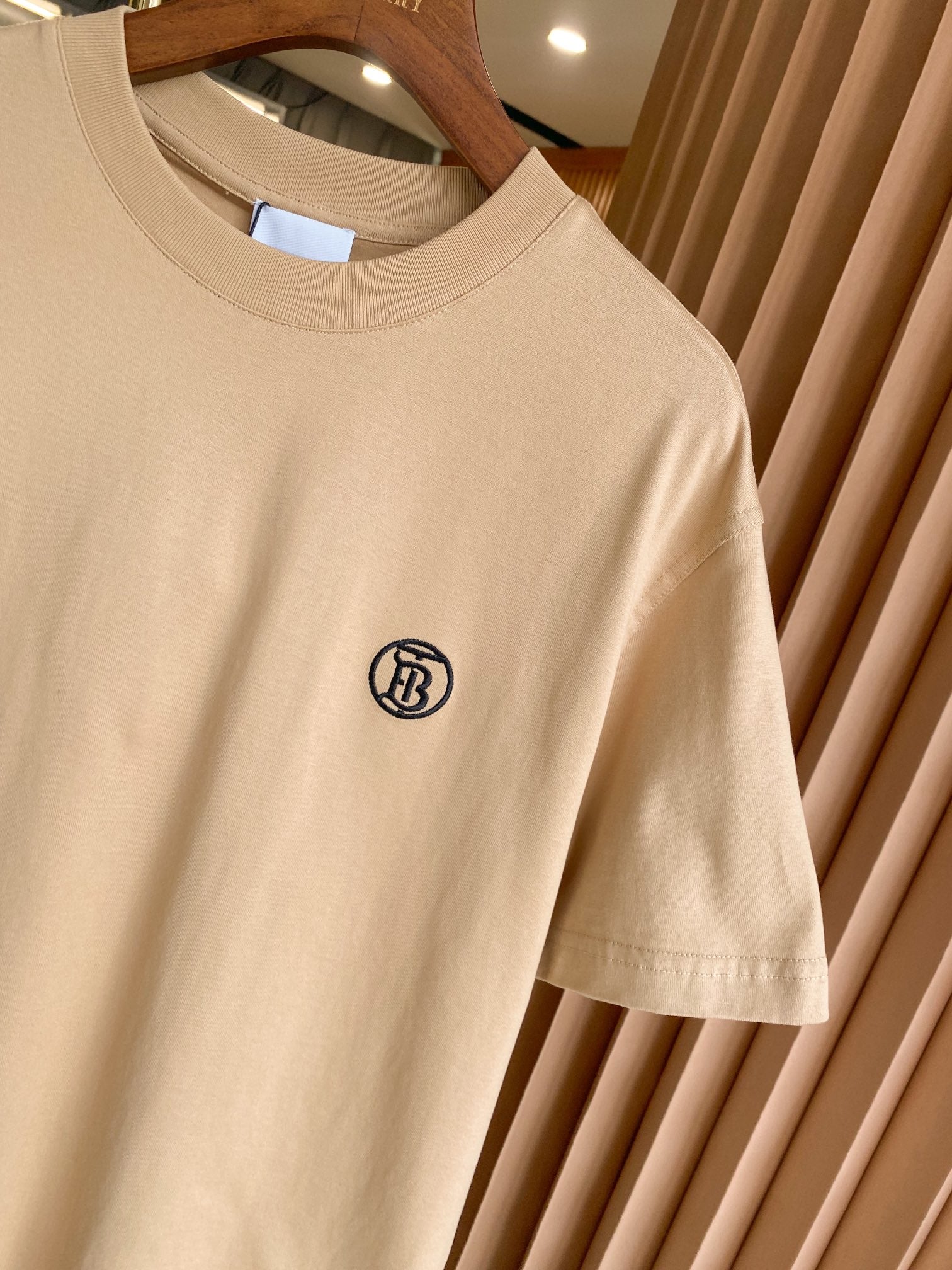 Light beige short-sleeve crewneck T-shirt with black circular chest logo