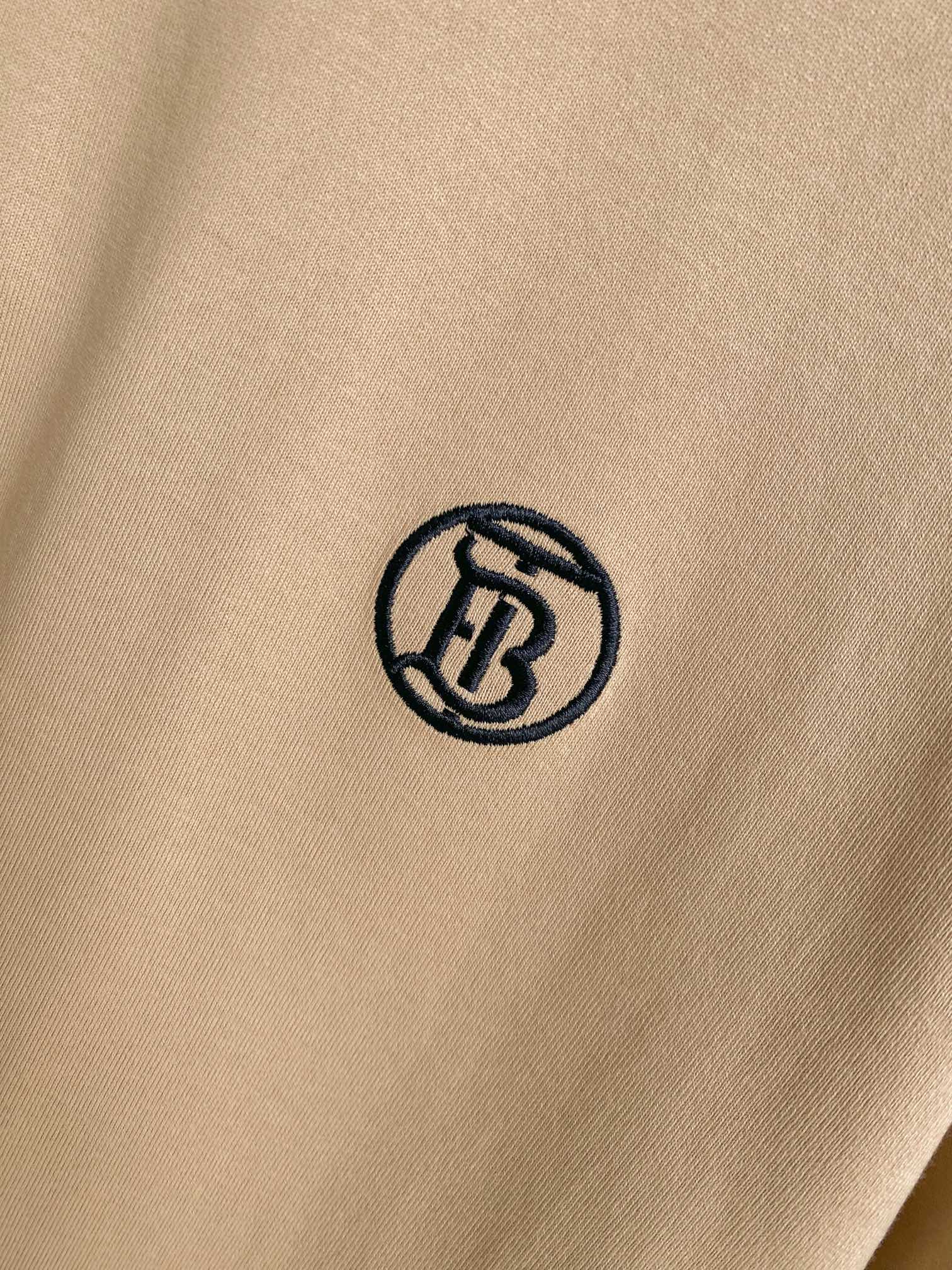 Close-up of black circular logo on light beige short-sleeve T-shirt fabric