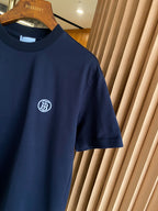 Navy crew-neck T-shirt with white circular emblem logo on left chest.