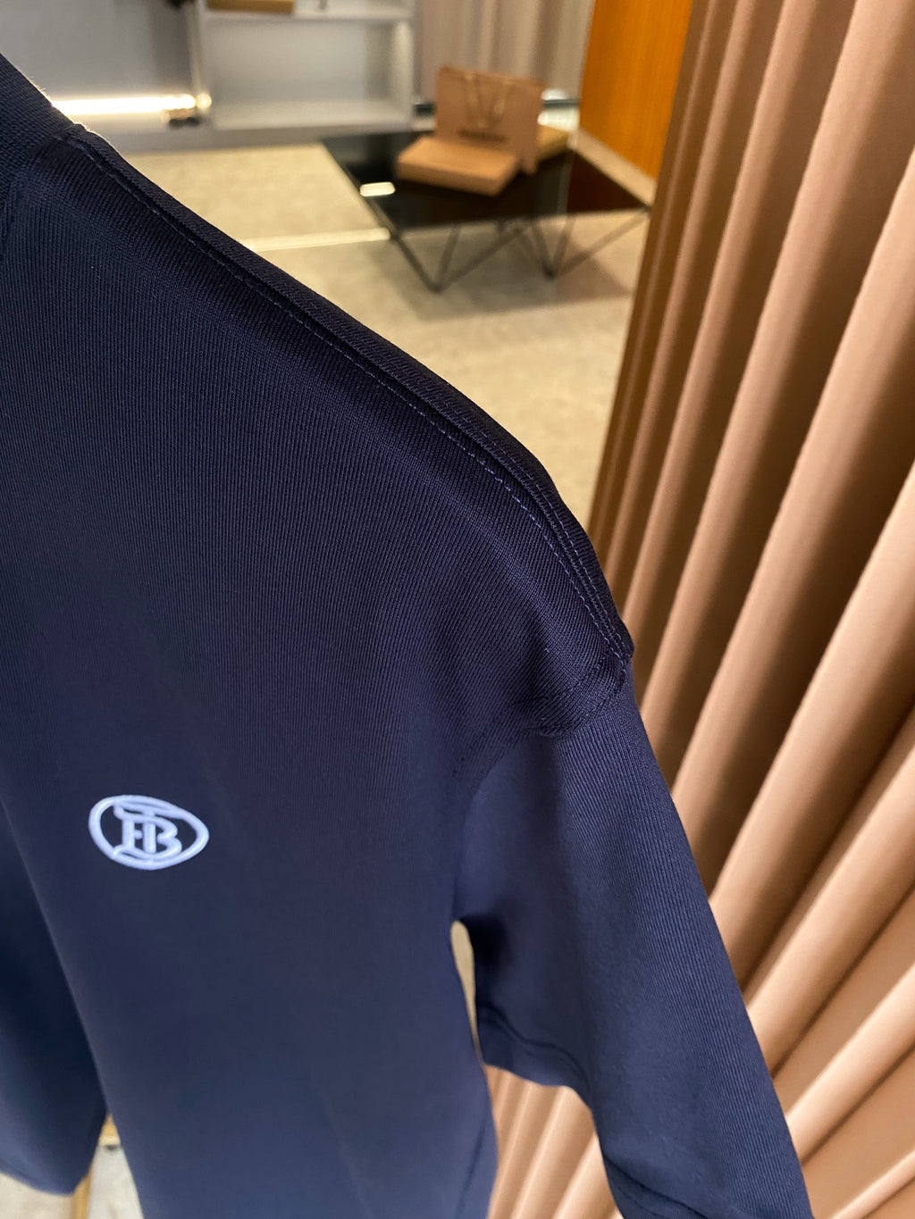 Navy short-sleeve T-shirt sleeve detail with white logo patch.