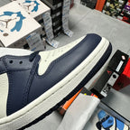 Air Jordan 1 low-angle view with navy leather, light blue accents, and white midsole