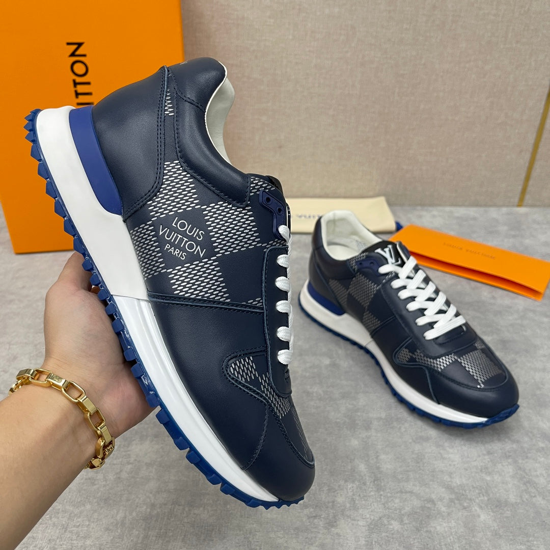 Navy Louis Vuitton low-top sneaker held in hand, white laces, diamond pattern, blue sole