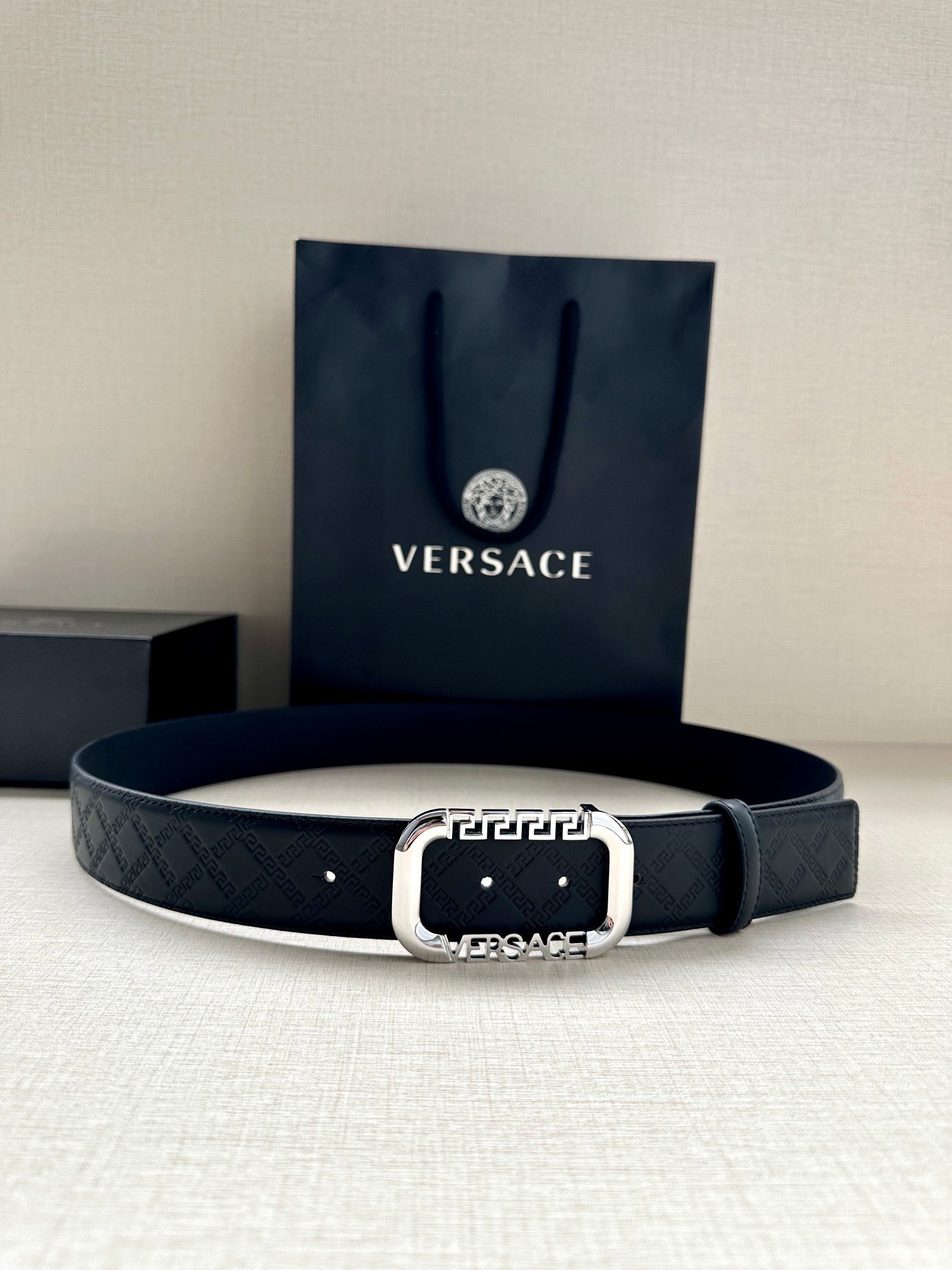 Versace belt in dark with embossed logo pattern and silver-tone round buckle.