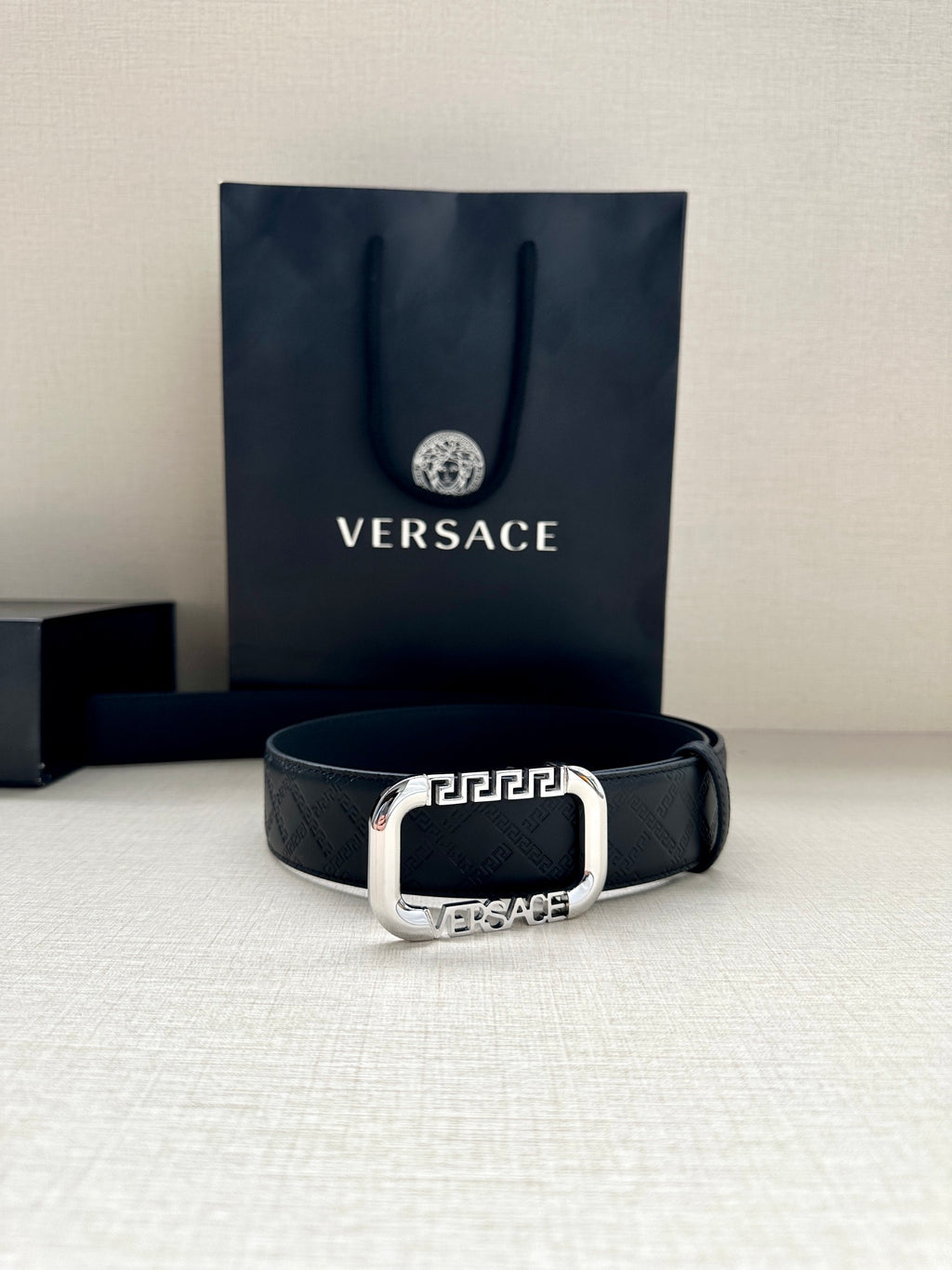 Versace belt in dark with embossed logo pattern and silver-tone buckle.
