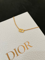 Gold-tone pendant necklace with logo-style motif on chain