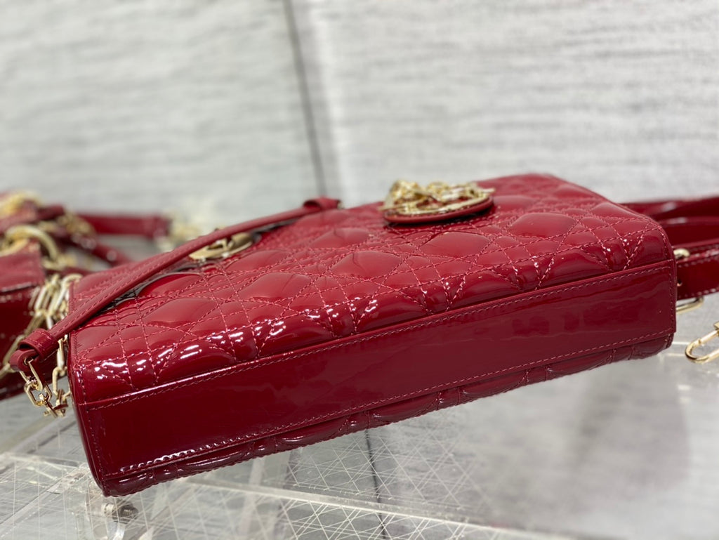 Dior handbag deep red glossy patent side view with gold top clasp hardware.