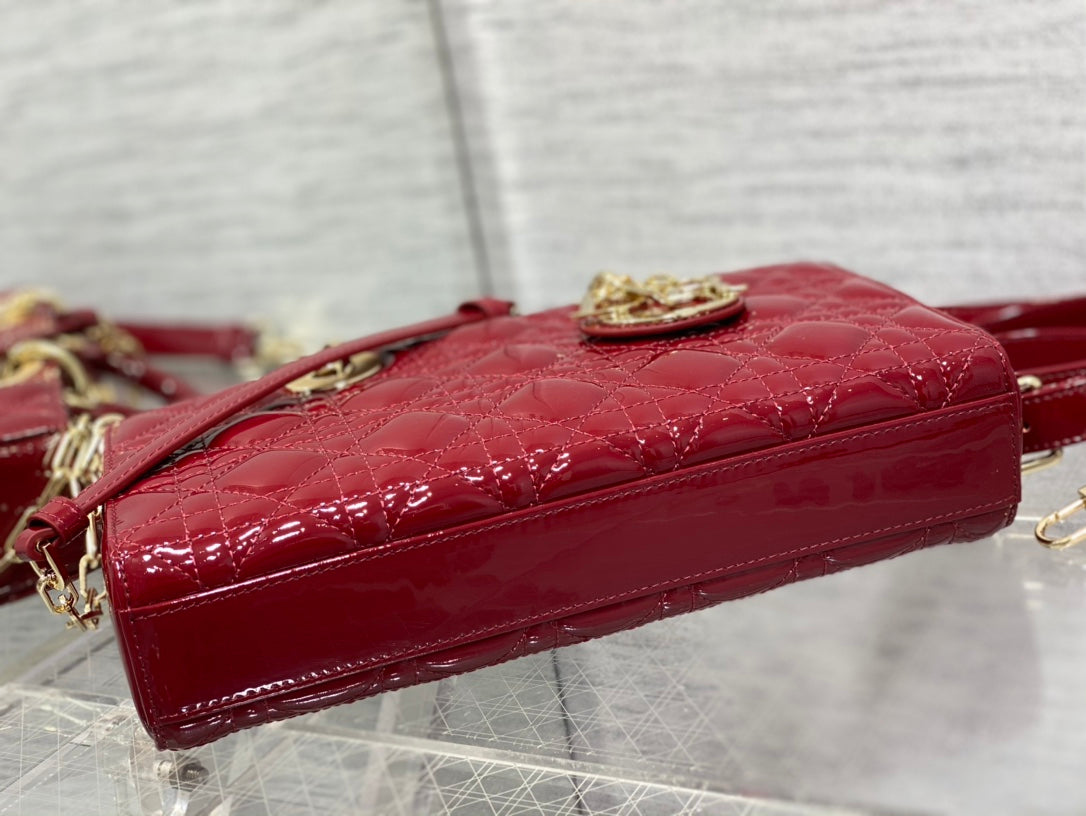 Dior handbag deep red glossy patent side view with gold top clasp hardware.