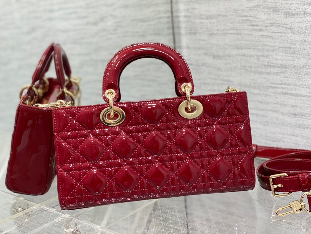 Dior handbag deep red quilted with two top handles and gold rings; strap attached.