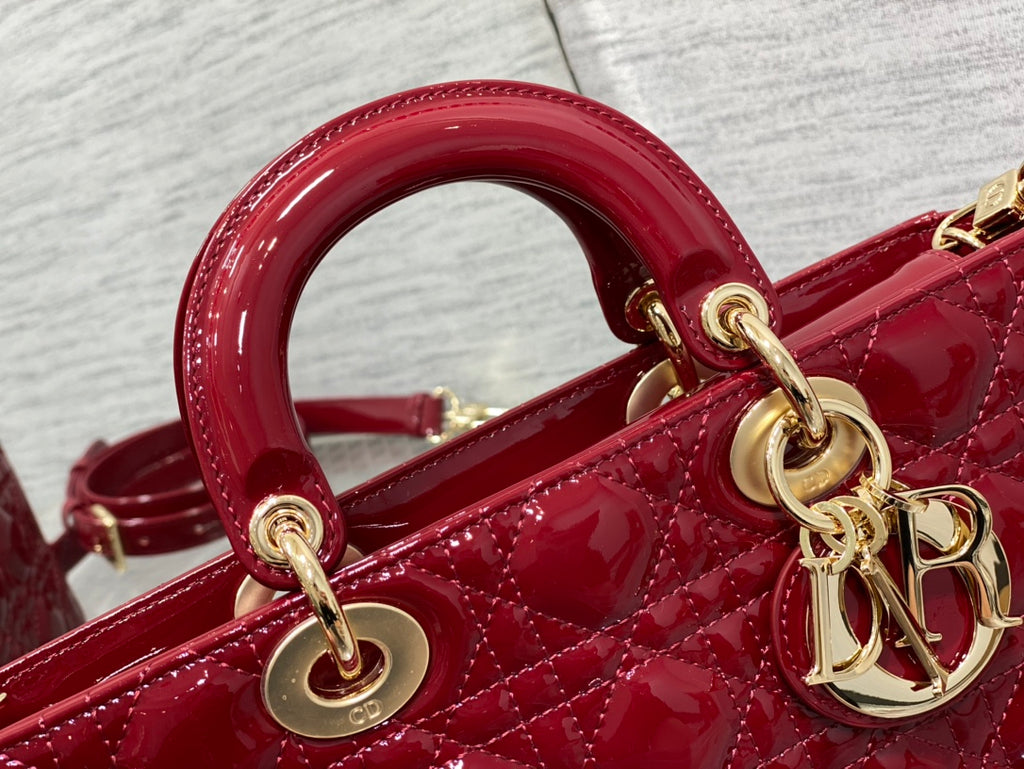 Dior handbag close-up: deep red top handle rings and gold chain hardware.