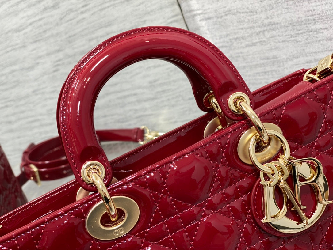 Dior handbag close-up: deep red top handle rings and gold chain hardware.