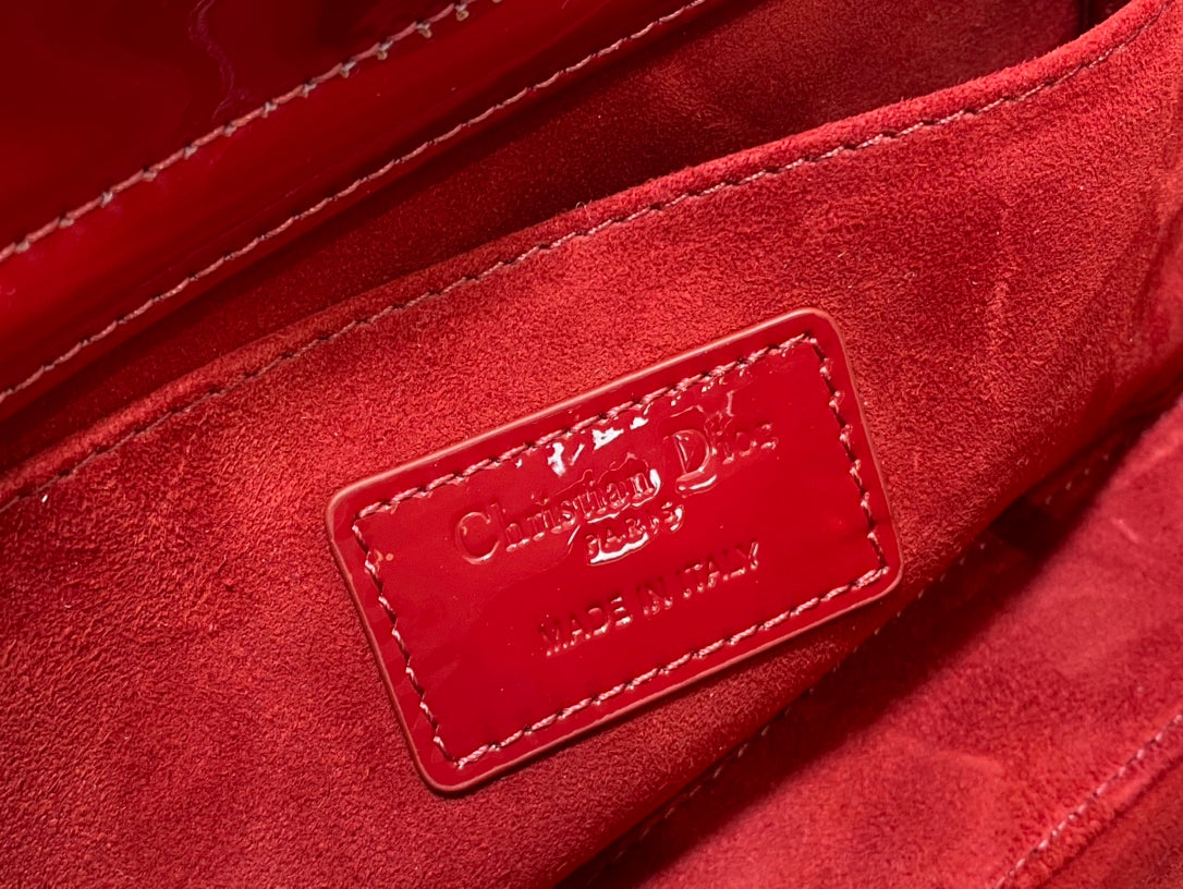 Dior handbag close-up of deep red fabric lining and logo patch.