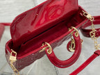 Dior handbag open view showing deep red interior, gold rings, and chain shoulder strap.