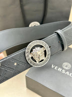 Dark leather belt with monogram texture and close-up gold Medusa buckle