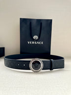 Dark navy patterned belt with round medallion buckle on a flat lay