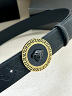 Dark navy belt buckle close-up with gold Greek key frame and lion emblem
