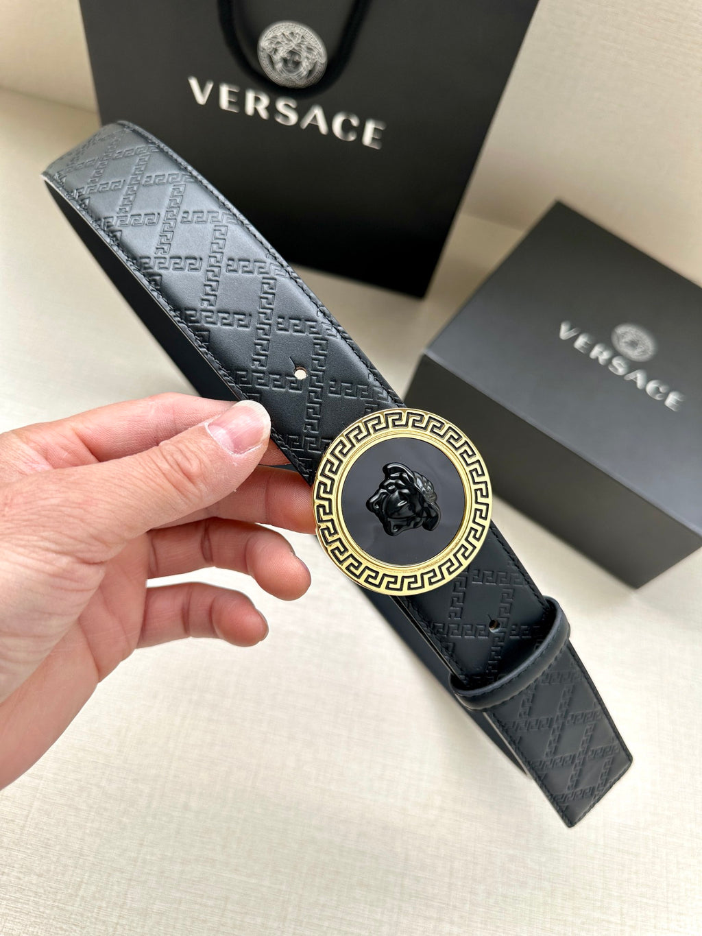 Dark navy patterned belt with gold-tone medallion buckle and Versace-style emblem