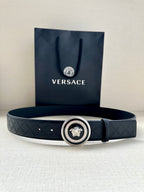 Versace belt lying flat: dark embossed strap with round medallion buckle