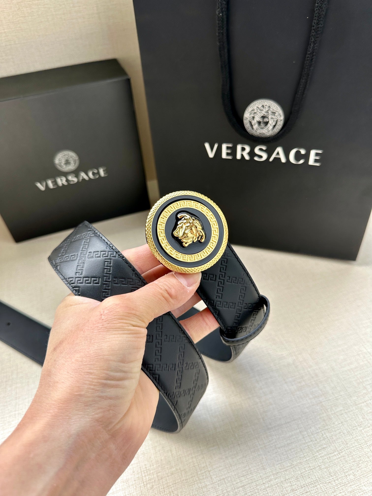 Versace belt with textured monogram strap and round gold-and-black medallion buckle