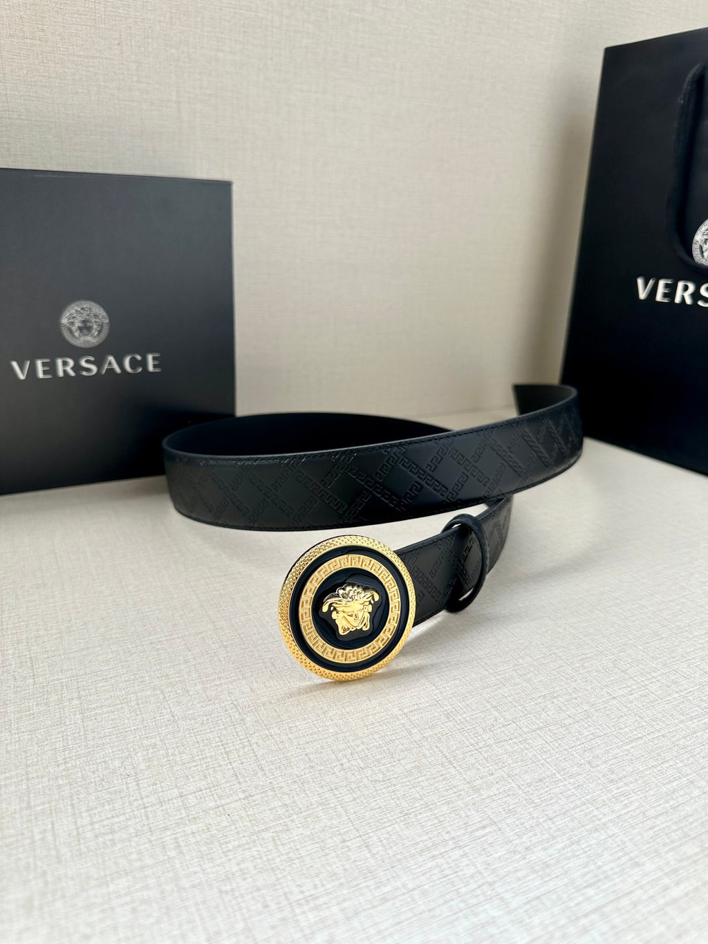 Versace belt, dark embossed strap with round gold-and-black medallion center buckle