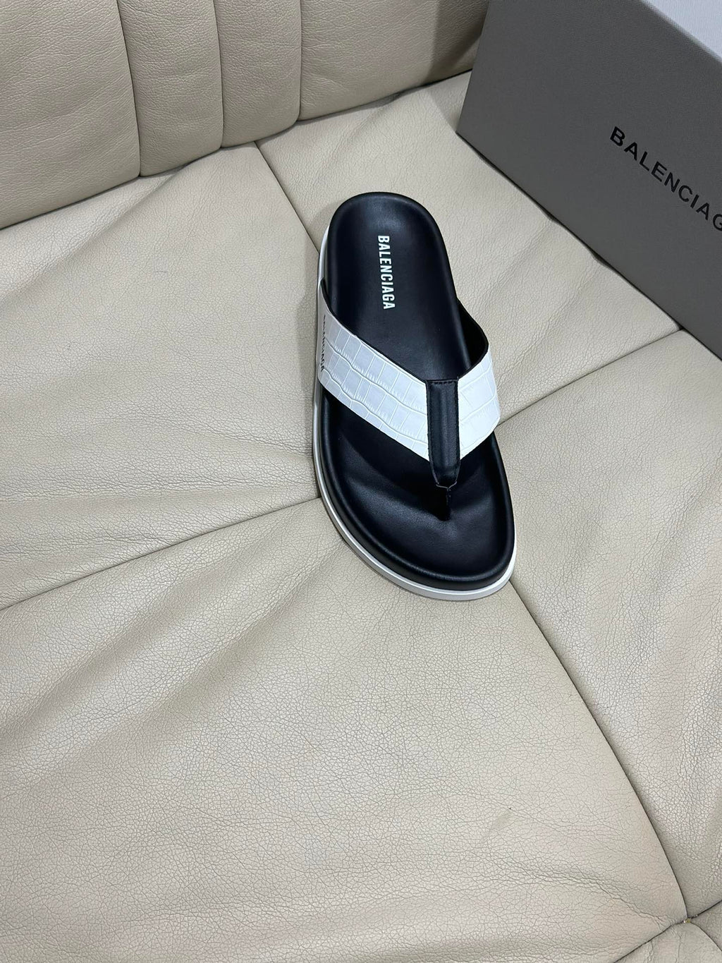 Single black flip-flop sandal with white cross strap and white midsole trim