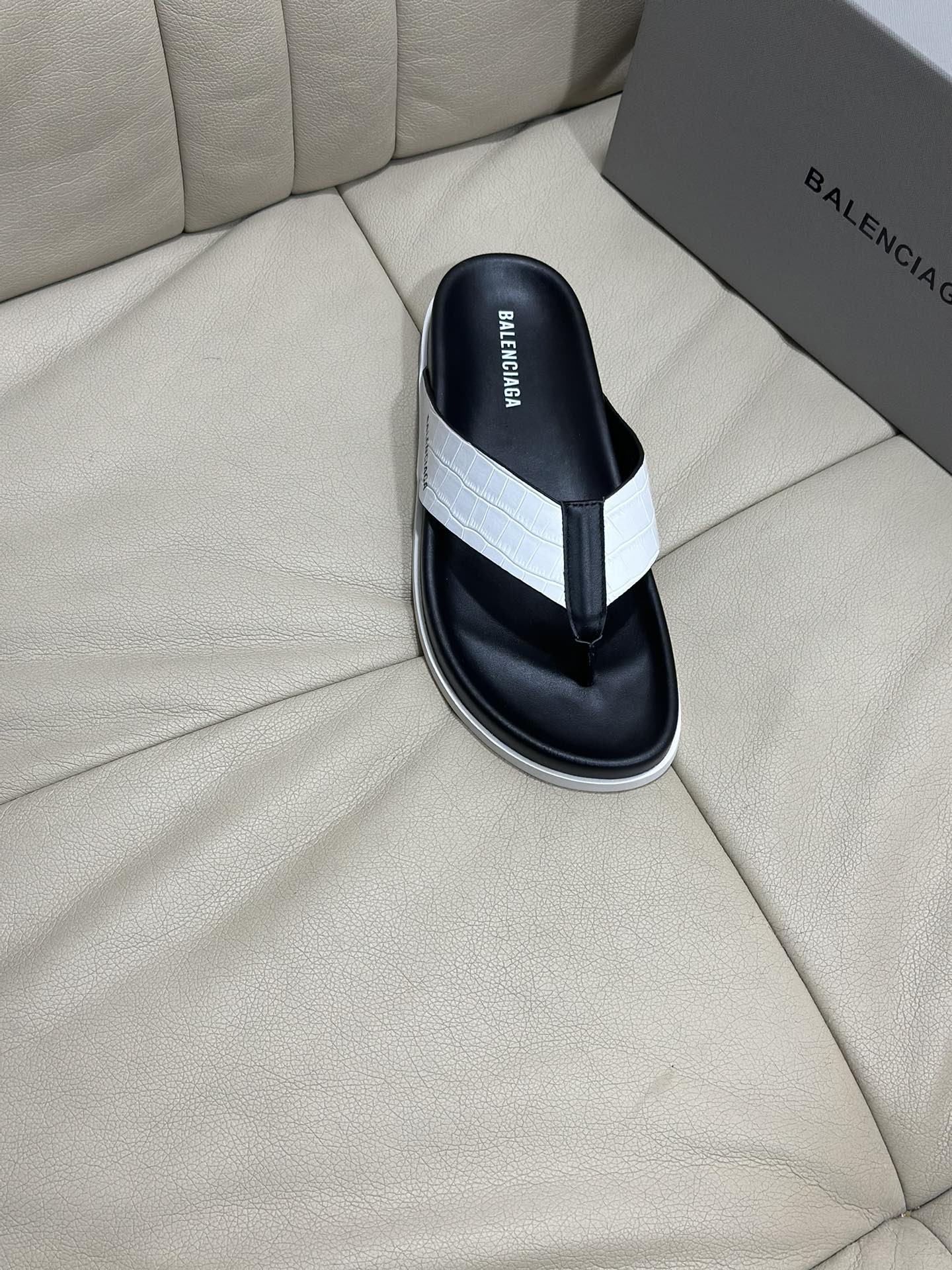 Single black flip-flop sandal with white cross strap and white midsole trim