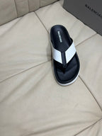 Black thong sandal with white strap and branded insole, upright on seat