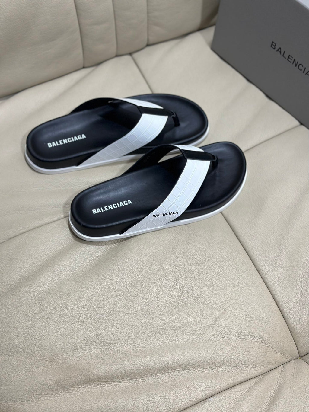 Black slide sandals with white thong strap and branded footbed detail