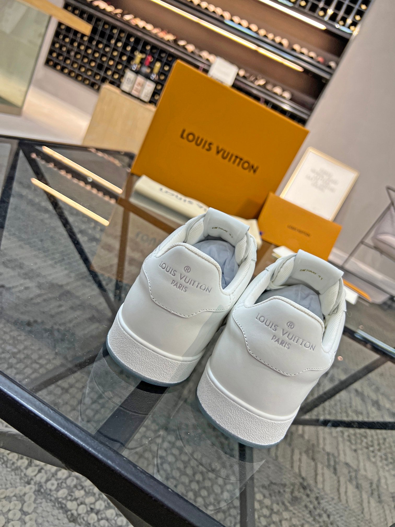 White Louis Vuitton sneakers viewed from the back, with rear logo on heel.