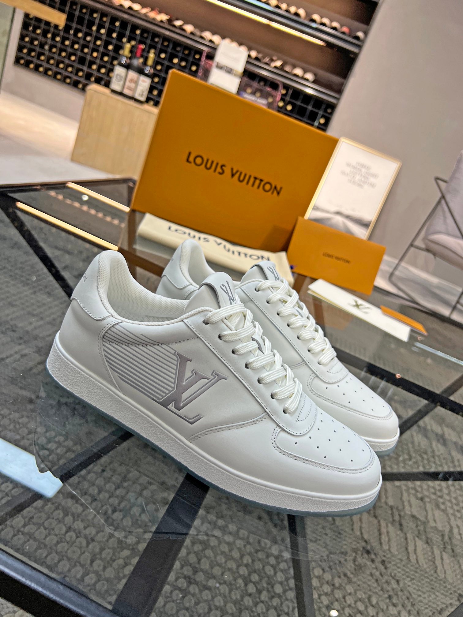 White Louis Vuitton low-top sneakers with LV logo detail and lace-up design.