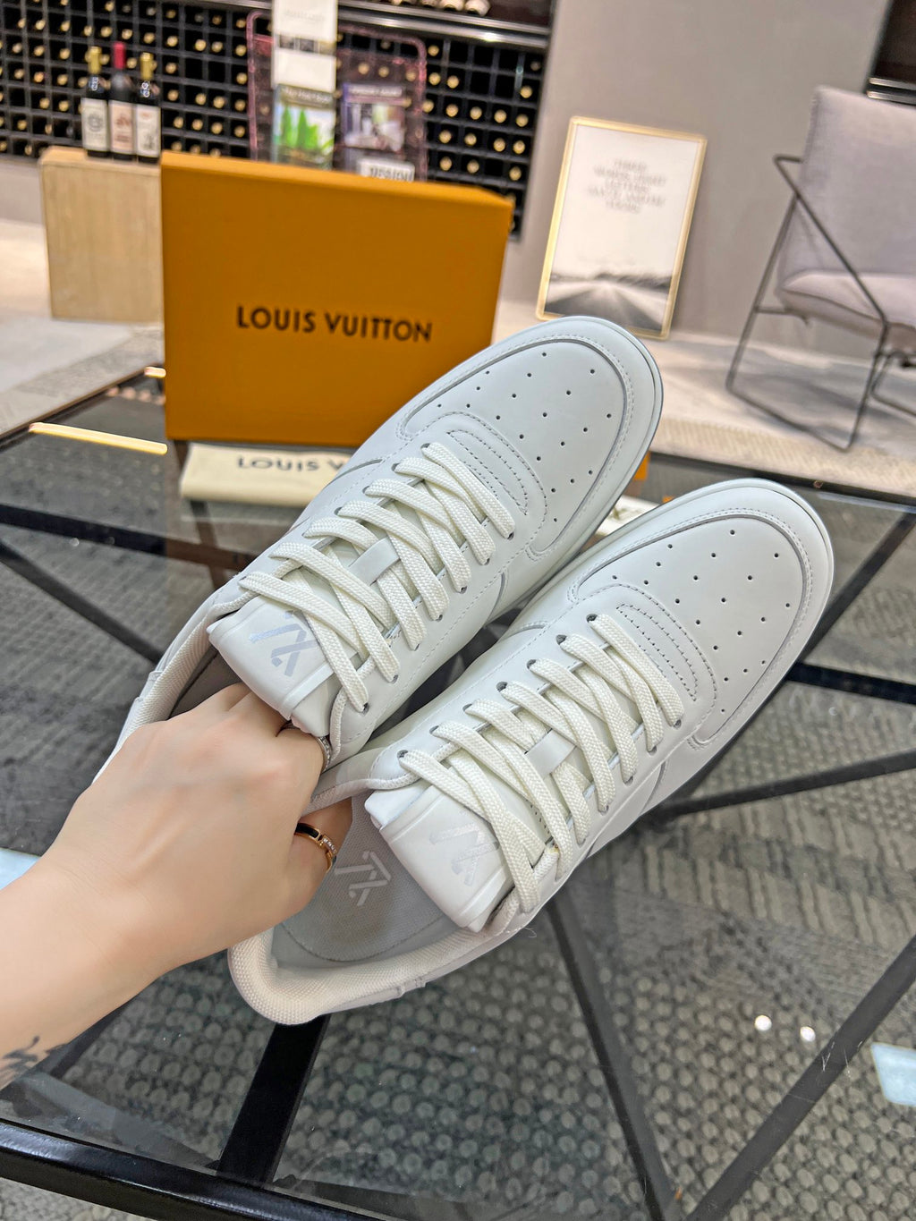 White Louis Vuitton lace-up sneakers showing laces and perforated toe caps.