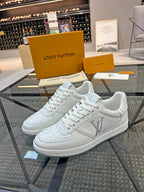 White Louis Vuitton lace-up sneakers with LV logo on side and perforated toe.