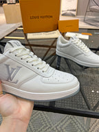 White Louis Vuitton sneaker showing LV side emblem and lace-up front.