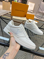 Pair of white Louis Vuitton low-top sneakers with LV logo on side, lace-up.