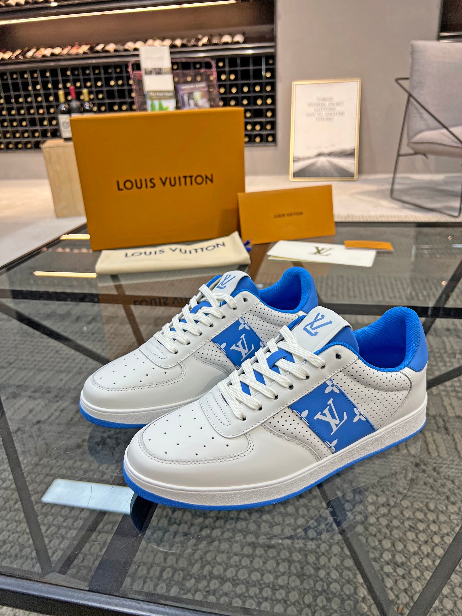 Louis Vuitton low-top sneakers with white uppers, blue logo patch, and white laces