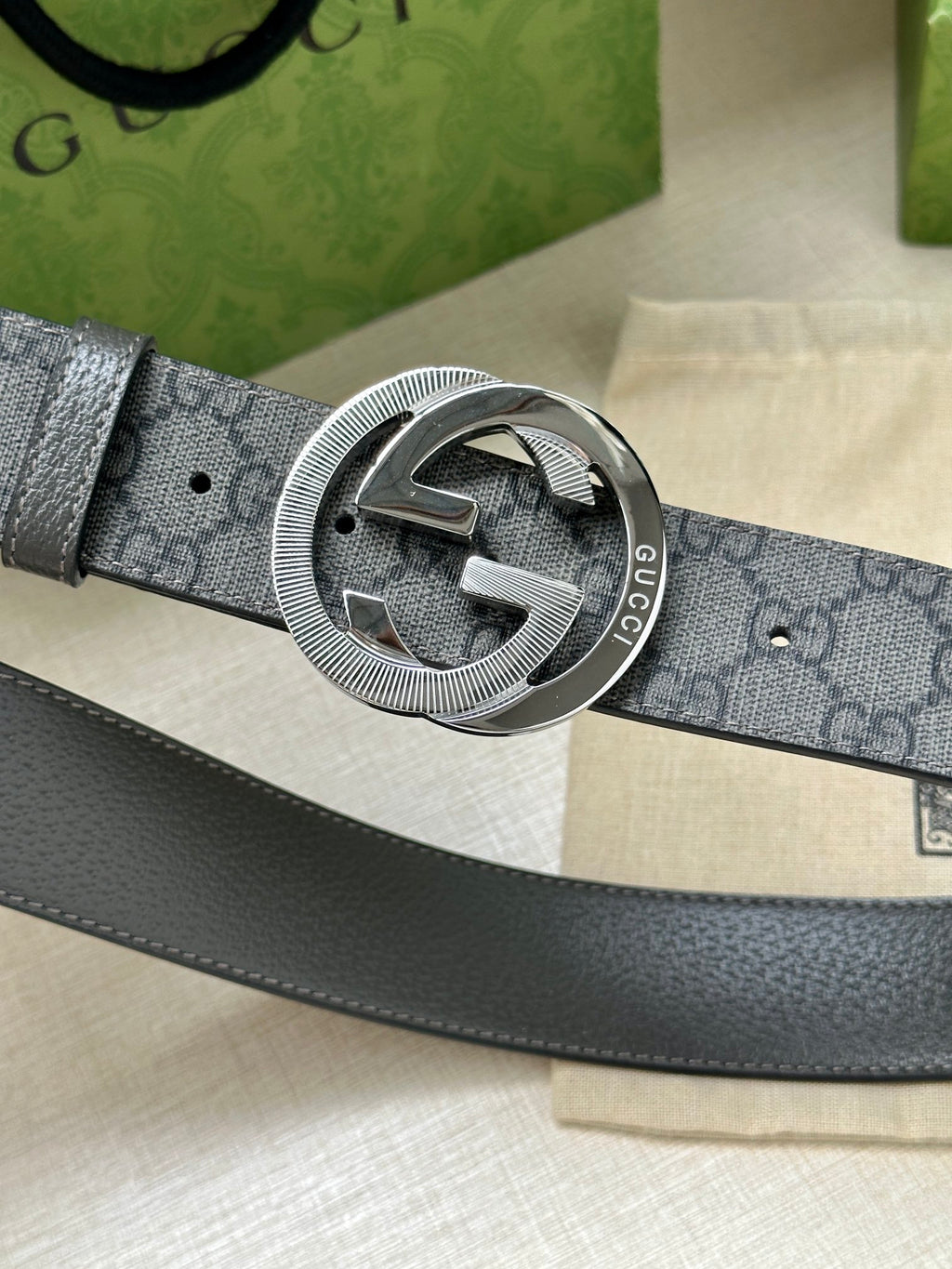 Gucci belt buckle close-up on dark gray GG canvas strap with silver-tone hardware