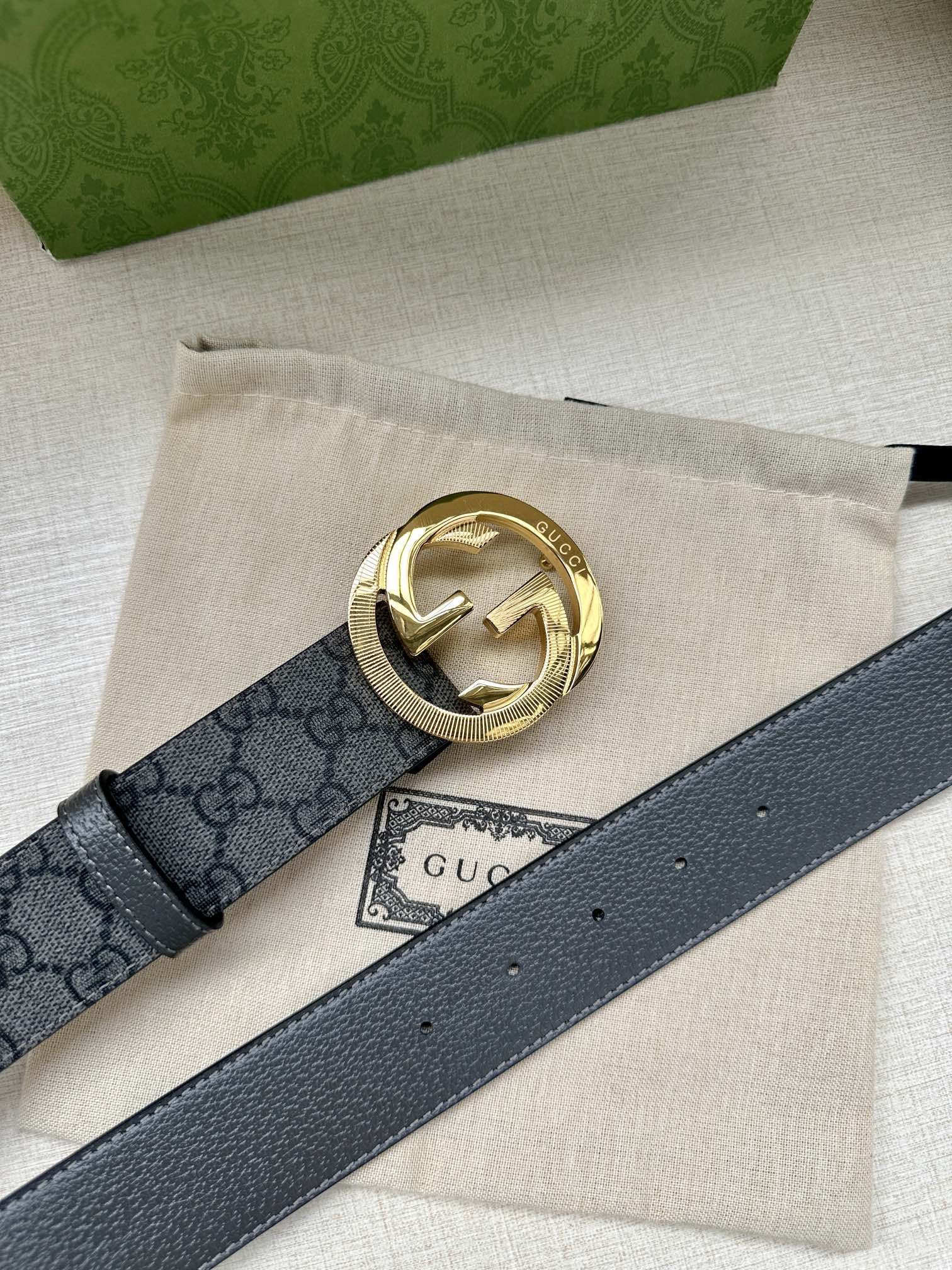 Gucci belt with dark gray GG canvas and gold-toned logo buckle on leather strap