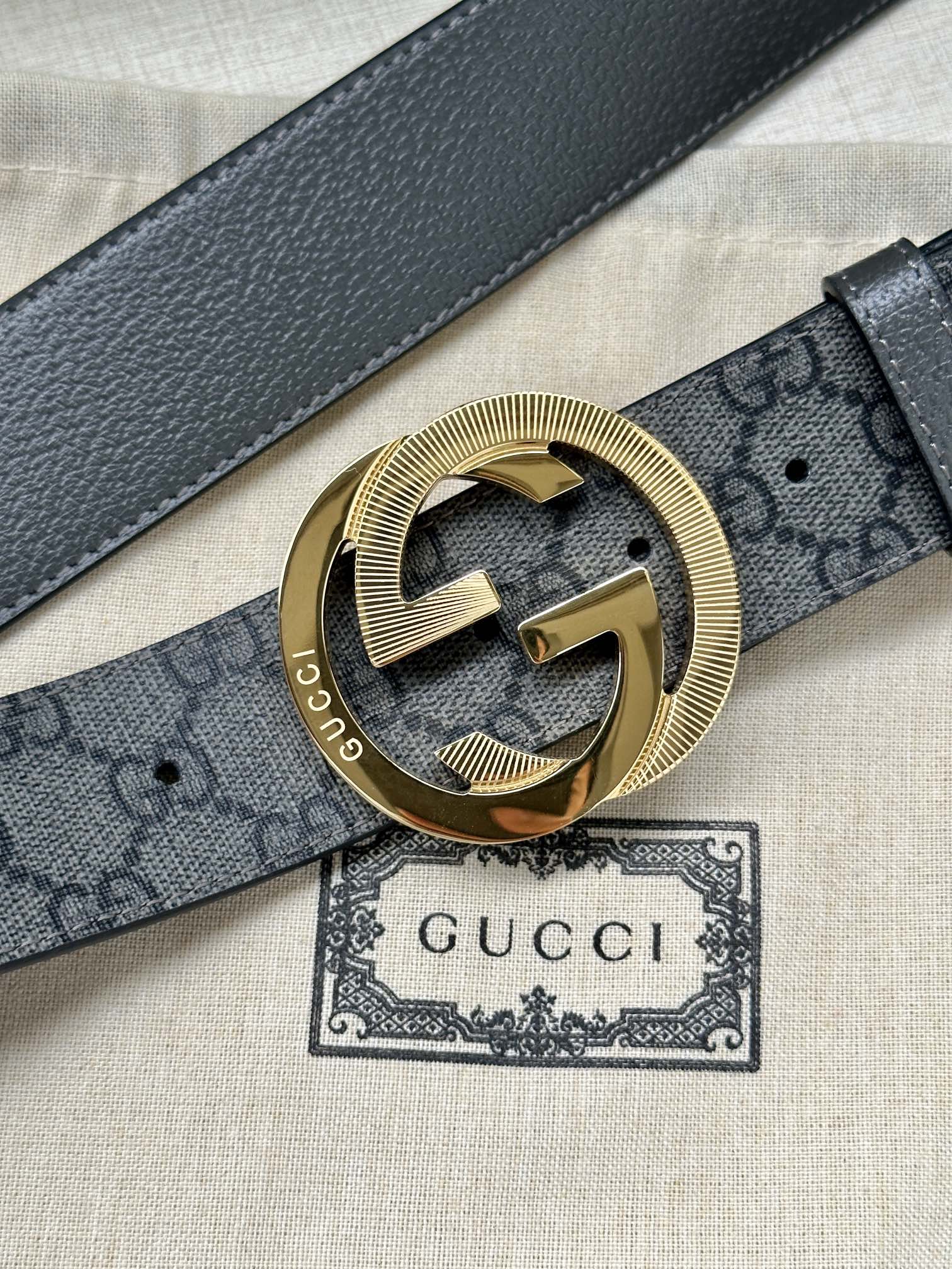 Gucci belt close-up: dark leather strap with GG canvas and gold-tone logo buckle