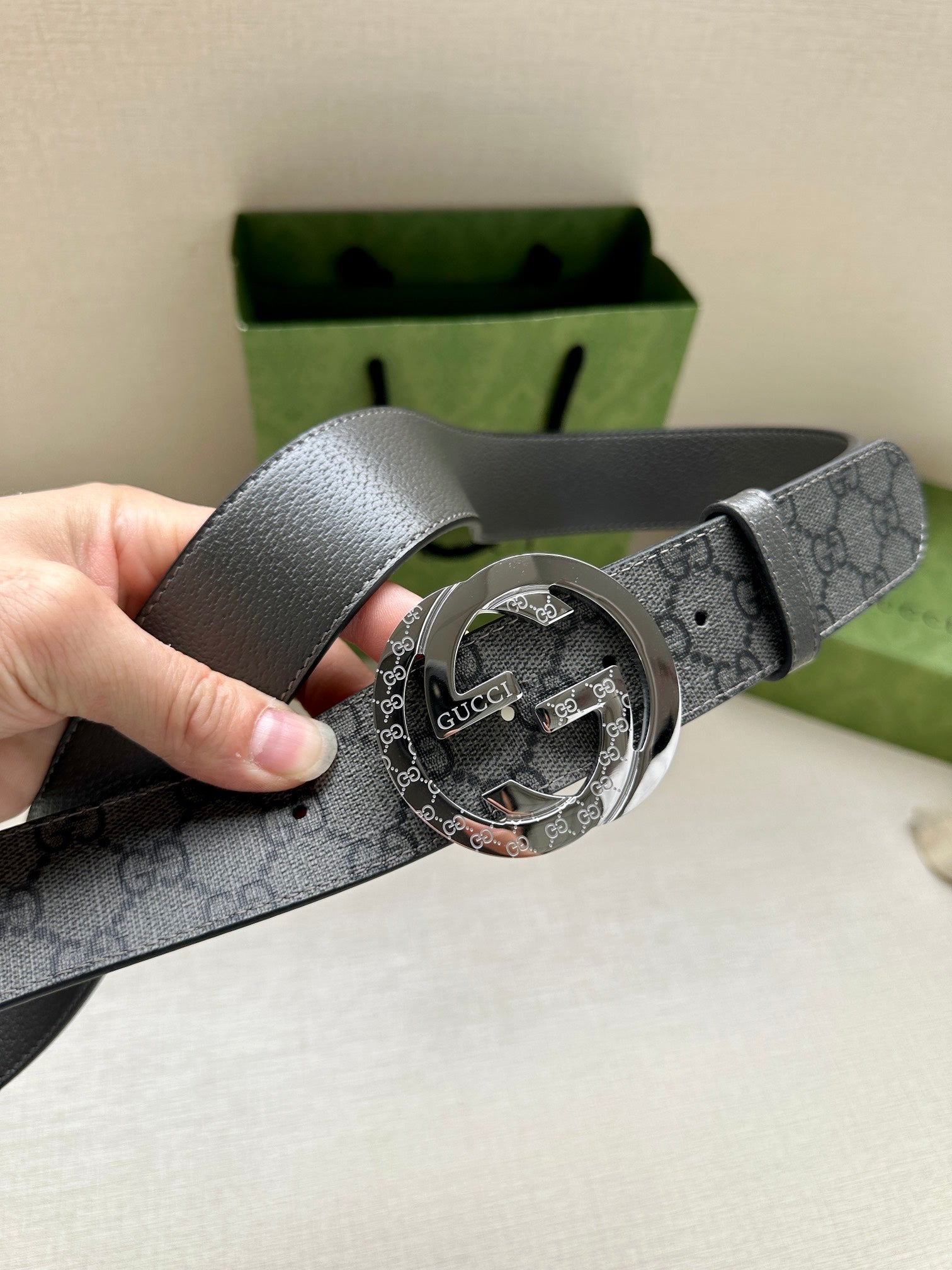 Gucci belt with dark gray GG monogram strap and silver-tone buckle close-up