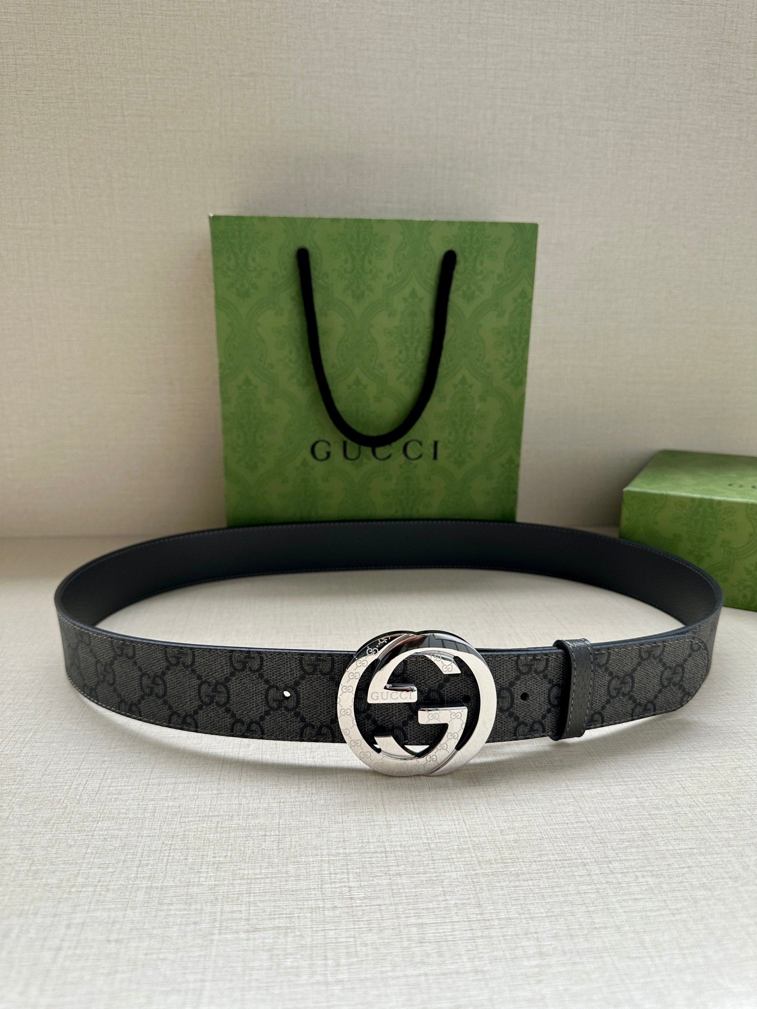 Gucci belt with dark gray GG monogram strap and silver-tone oval logo buckle