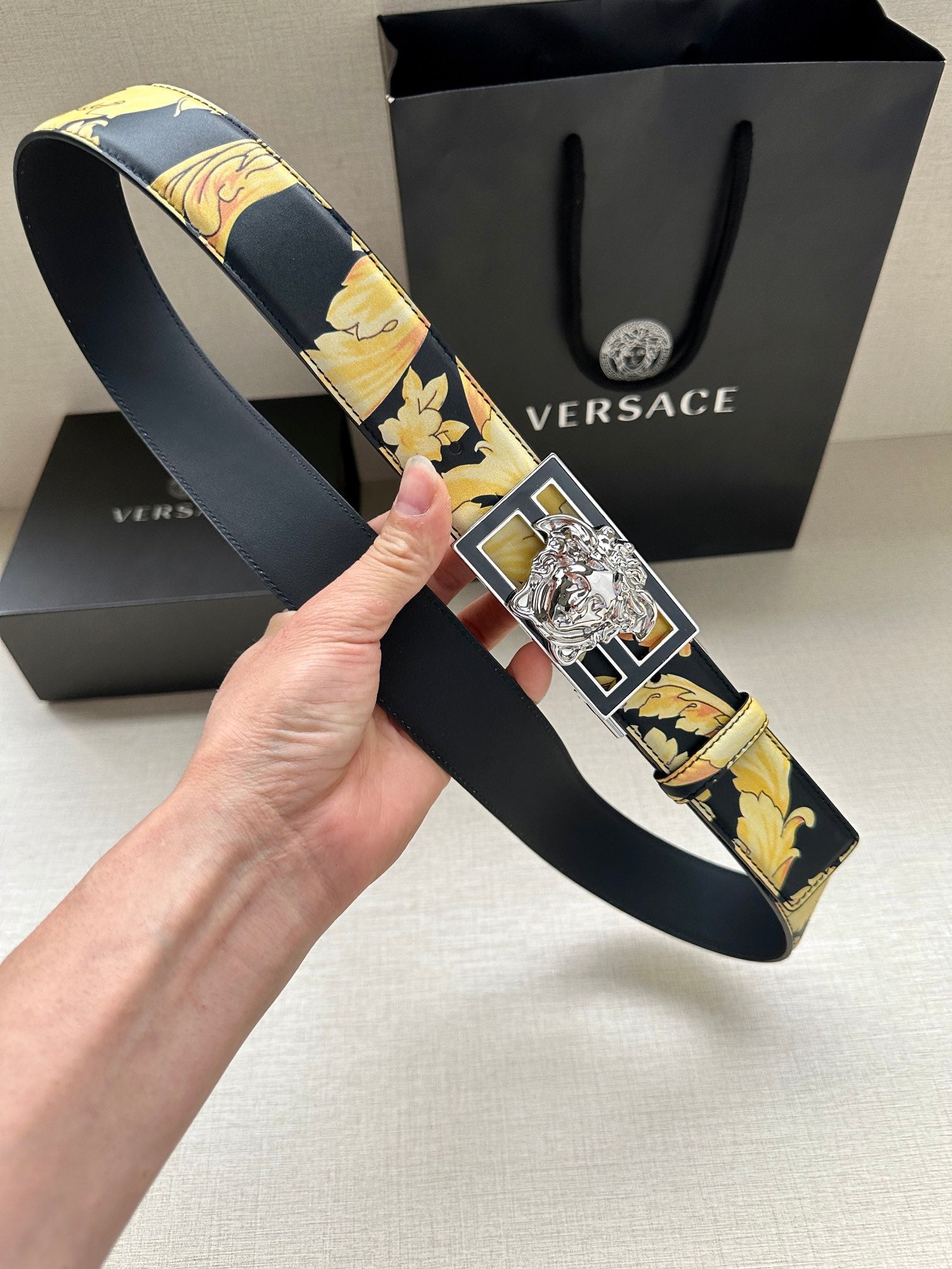 Versace belt with dark navy floral strap and large silver-tone Medusa buckle detail.