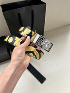 Versace belt angled view with navy leather and gold flower pattern, metal buckle.