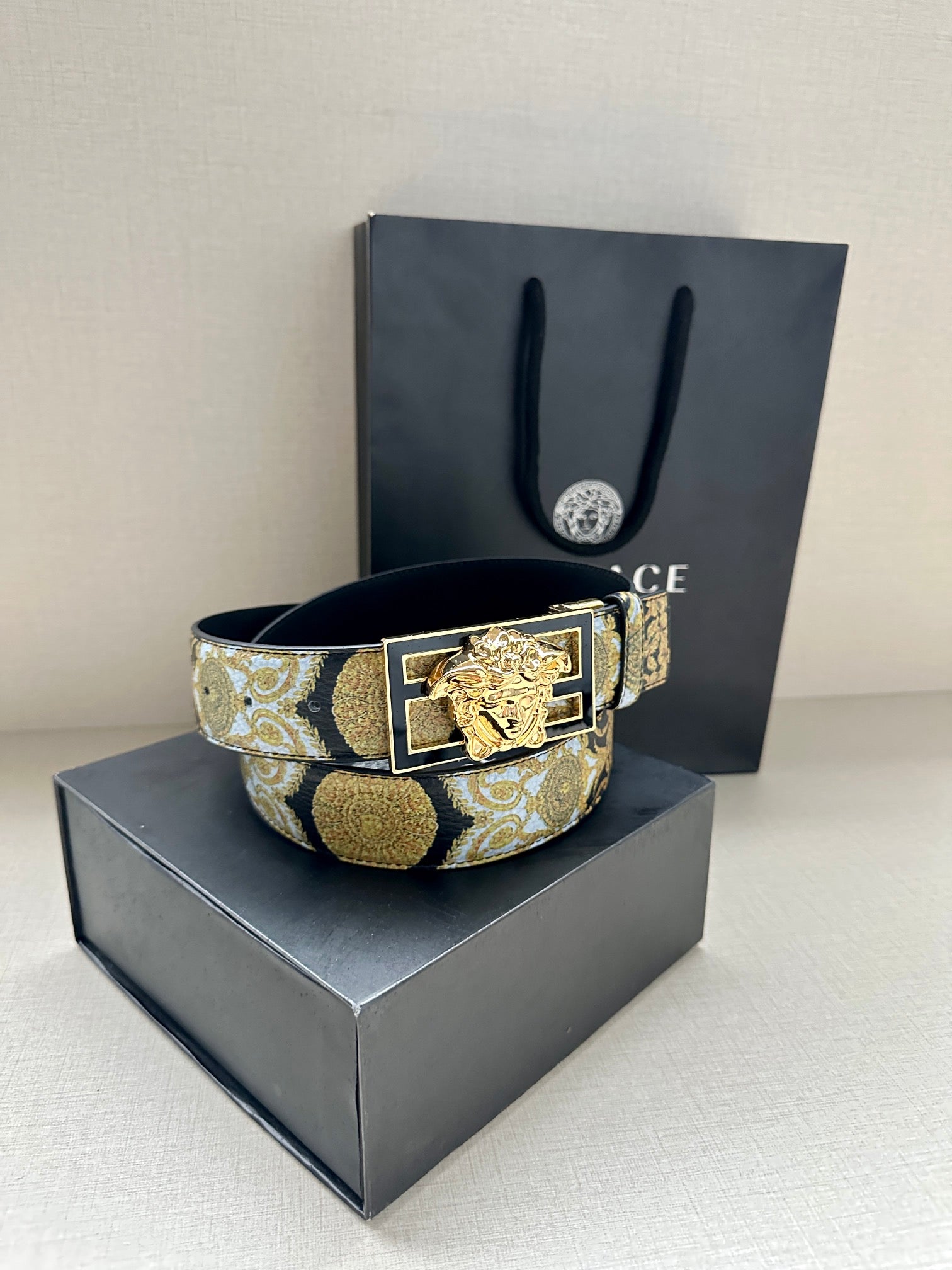 Versace belt with gold-blue patterned strap and gold lion buckle on stand