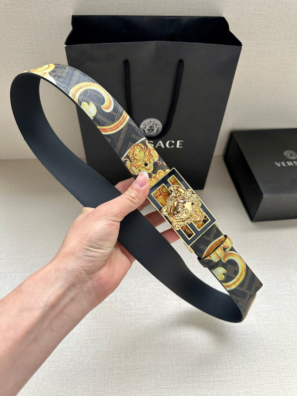 Designer belt held up: navy baroque patterned strap with gold medallion buckle