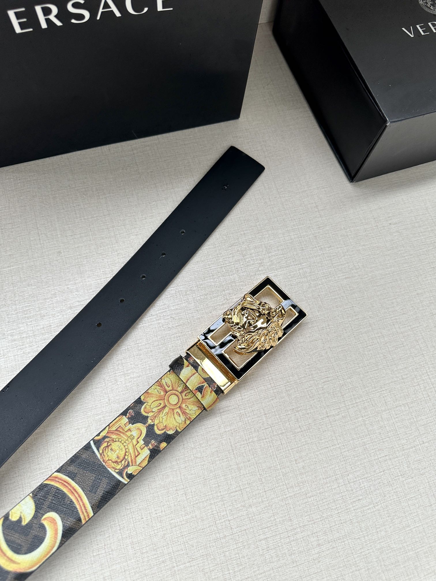 Designer belt laid flat with navy patterned strap and gold baroque buckle